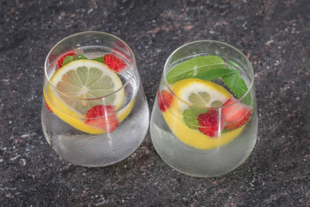 Cold water with berries and lemon in two glasses.
