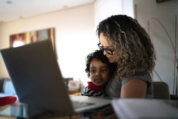 istock Mature woman working at home, carrying young son 1255718527