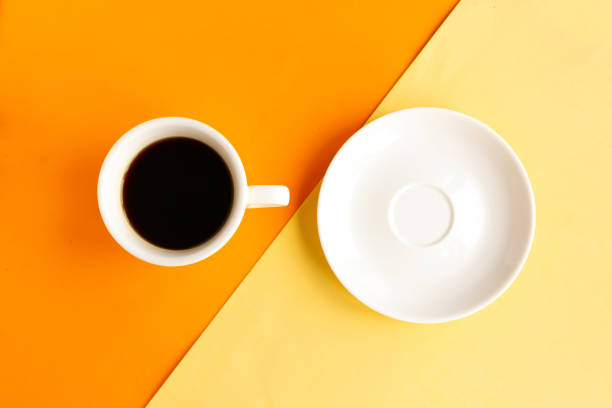 istock White plate and coffee cup on geometric orange and yellow background, top view. Minimal concept 1255718546