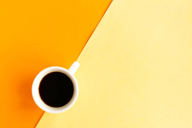 istock Coffee cup on geometric orange and yellow background, top view, copy space for the text, minimal concept 1255718597