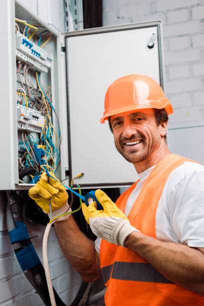 istock Smiling electrician holding insulating tape and wires while fixing electric panel 1255719293