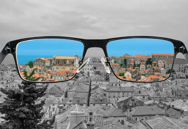 Photo of Different perception of world. Colorful view of red roods and blue sea in  Looking through glasses.