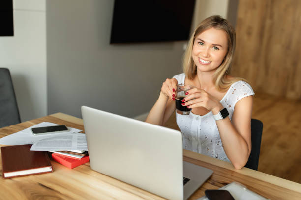 istock Woman with coffee working on laptop computer at home office 1255721404