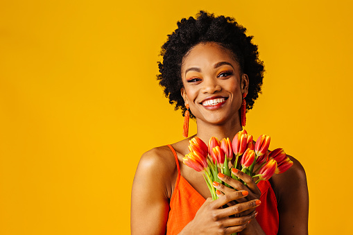 Portrait of a happy smiling young woman with orange tulips bouquet