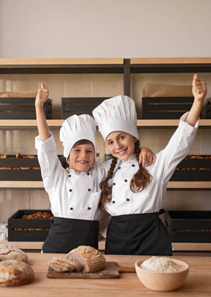 glada små bagare gestikulerar tummen upp - boy and girl in kitchen thumbs up bildbanksfoton och bilder