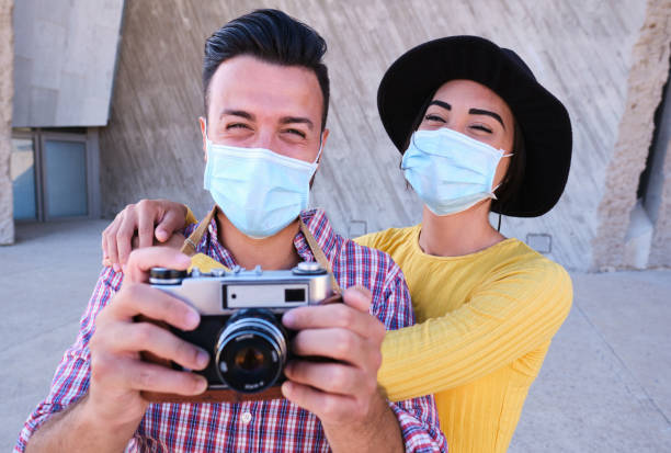 Young couple with mask photographing in the streets stock photo