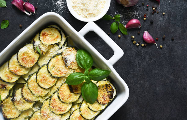 Zucchini casserole with cream, garlic and parmesan on a black background. View from above. stock photo