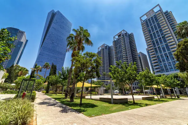 Tall modern business and residential buildings under blue sky as seen from Sarona market in Tel Aviv, Israel (low angle view).