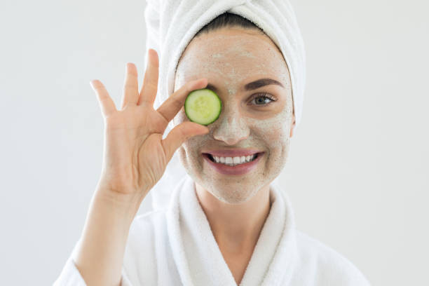 young woman playing with cucumber slices - facial mask spa treatment cucumber human face imagens e fotografias de stock