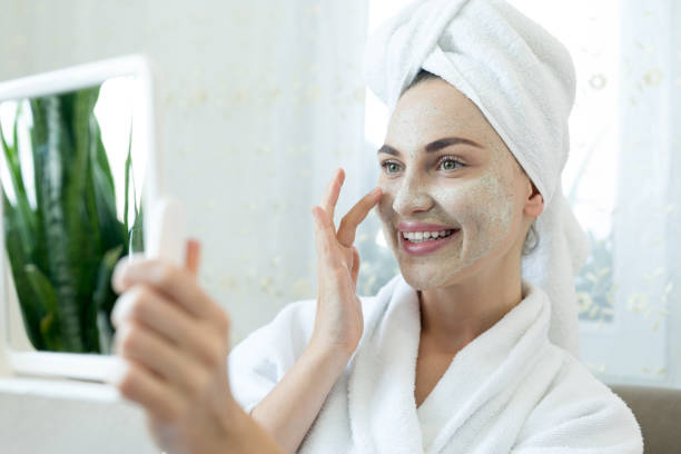 istock Young woman applying facial mask 1255741703