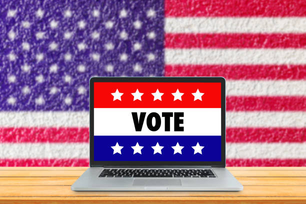 istock VOTE text wording on laptop display with USA flag in background. 1255743404