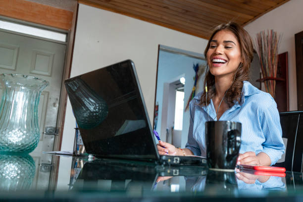 A beautiful executive has a meeting with colleagues in the office while at home working from her desk and wearing her dress.