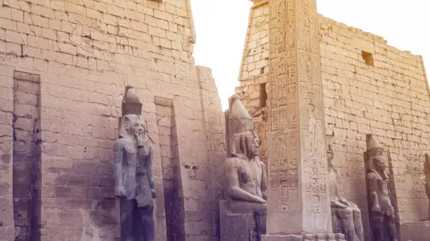 Photo of obelisk column at Luxor temple entrance with pharoah scultures background