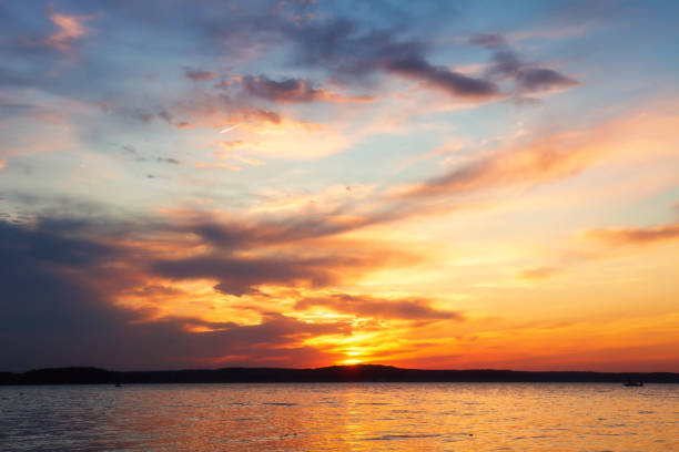 Summer. Picturesque landscape. Beautiful red sunset above lake. Dark clouds close up sunset.