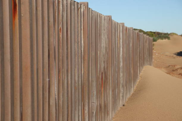 istock A border fence built on beach sand. Immigration control concept image. 1255750619
