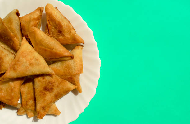 Triangular Arabic chicken samosa on bright green background with copy space