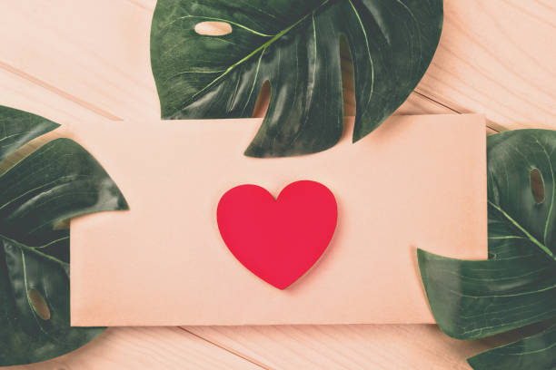 istock flat lay red wood heart lies on craft envelope on rustic table with three sheets of monstera in the corners 1255760506
