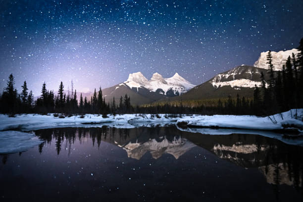 scène de nuit alpine avec le ciel plein d’étoiles et de montagne reflétée dans la surface d’eau - lake night winter sky photos et images de collection