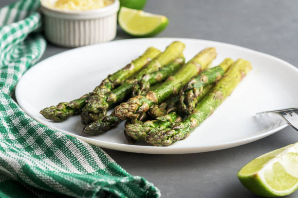 istock Appetizingly cooked asparagus with pieces of lime on a grey concrete table. 1255764529
