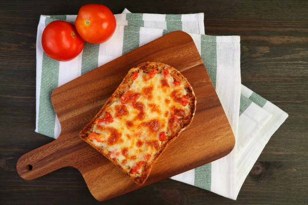 widok z góry na świeże pieczone domowe tosty do pizzy na desce do krojenia z świeżymi pomidorami na tkaninie kuchennej - breadboard zdjęcia i obrazy z banku zdjęć