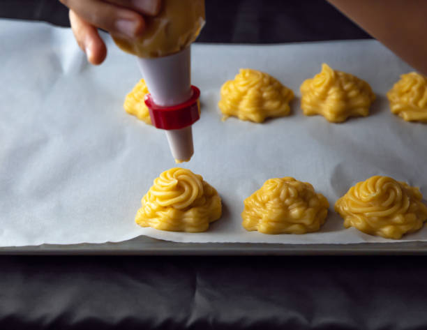 istock Piping Profiterole pastries onto a cookie baking sheet. 1255772016