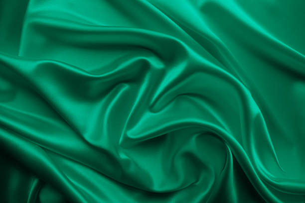istock Beautiful elegant wavy emerald green satin silk luxury cloth fabric texture. 1255774453