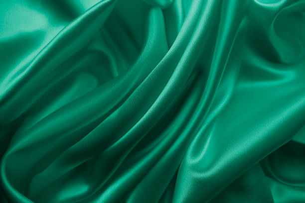 istock Beautiful elegant wavy emerald green satin silk luxury cloth fabric texture. 1255774476