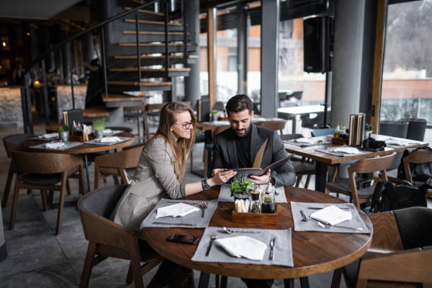 istock Well dressed couple sitting in restaurant and choosing what to eat from menu 1255776077