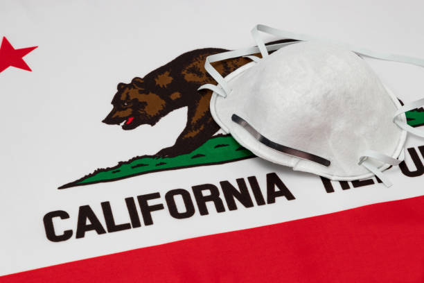 California state flag and N95 face mask. Concept of state and local government face covering mandate, order, requirement and social distancing during Covid-19 coronavirus pandemic background, no people mandate stock pictures, royalty-free photos & images