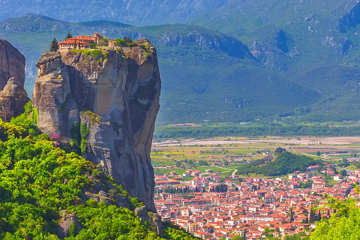 Holy Trinity Monastery on cliff rock top, Meteora, Greece and Kalampaka town in the valley
