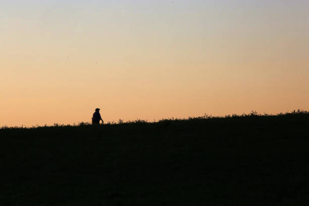 istock Silhouette of a Man Walking Up a Hill 1255782252