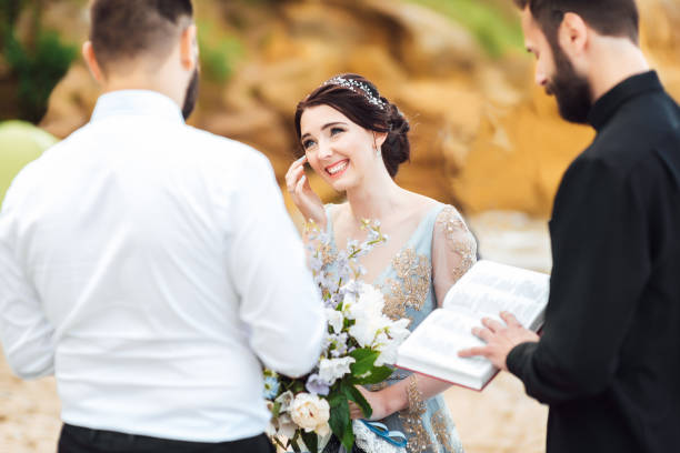 istock wedding couple on the ocean with a priest 1255784531