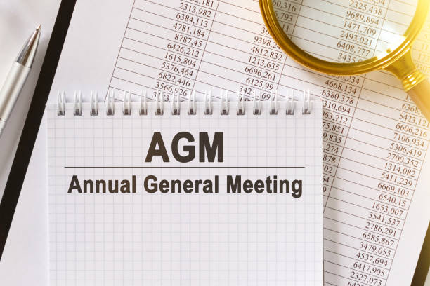 istock On the table are financial reports, a pen, a magnifying glass and a notebook with the inscription - AGM. 1255786063