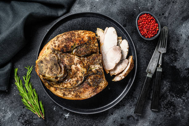 istock Roasted sliced pork ham on a plate.  Shank meat.  Black background. Top view 1255787087