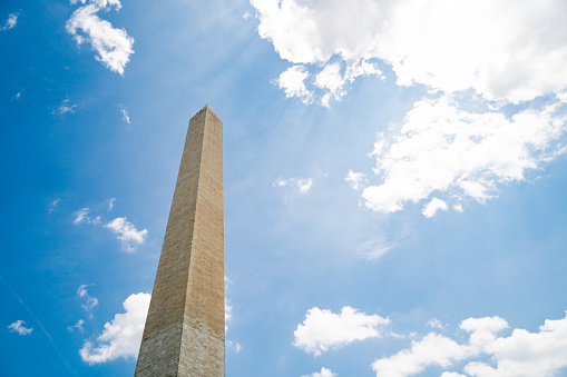 A waiving American flag in front of the Washington monument