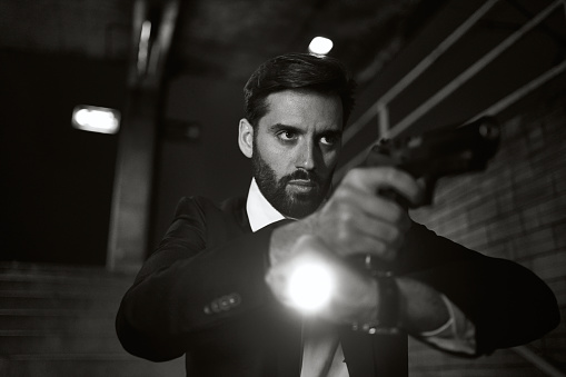Secret agent holding a gun isolated over black background