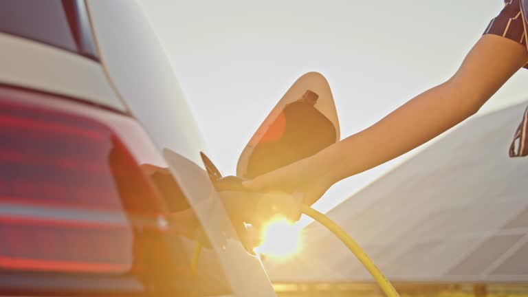 SLO MO Young woman charging her car with a power from solar panels