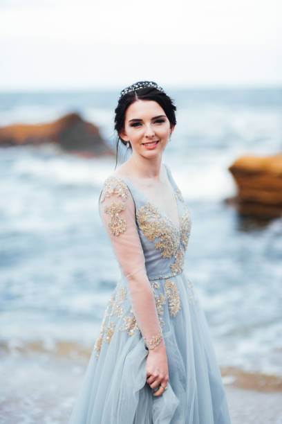 istock bride in a blue light dress walking along the ocean 1255789435