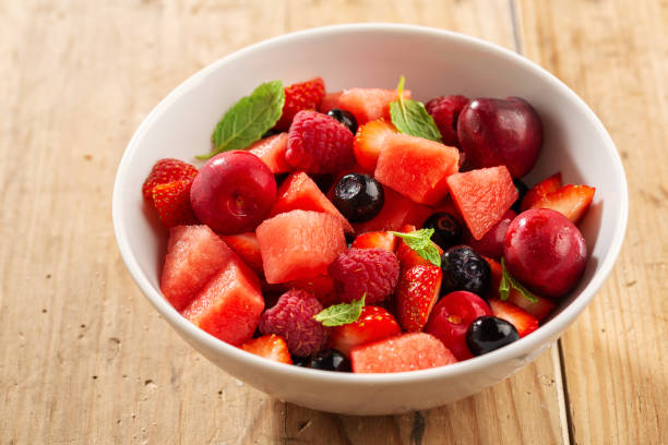 istock Tasty summer berries cut in bowl with mint. Closeup 1255789575