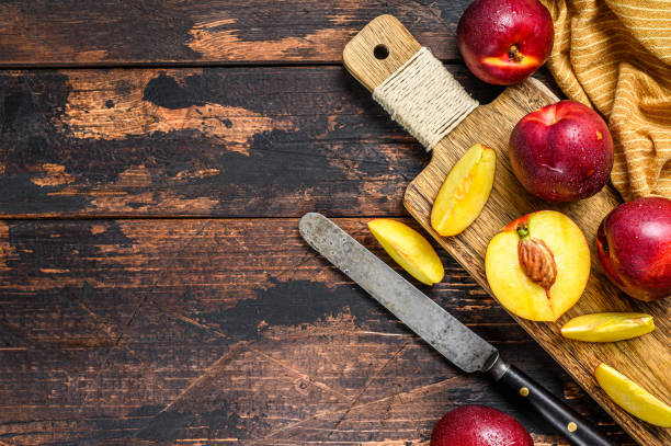 istock Sliced ripe red nectarines on a chopping Board. Dark Wooden background. Top view. Copy space 1255790103