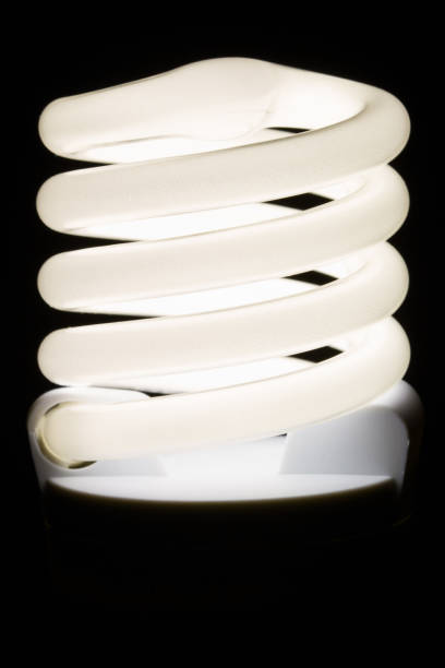 istock Fluorescent light bulb isolated on black background. Economical home lighting. Energy saving concept. 1255794495
