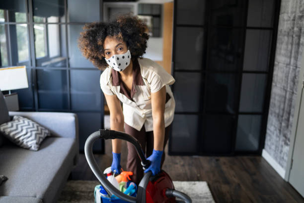 giovane donna che indossa una maschera protettiva per il viso e guanti mentre lavora in un hotel - home interior sparse bedroom inside of foto e immagini stock