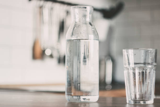 графин воды на кухонном деревянном столе. бутылка воды. концепция здорового образа жизни - decanter стоковые фото и изображения