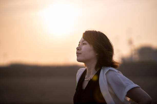 istock Young woman looking at far away, standing on beach at sunset time 1255802520