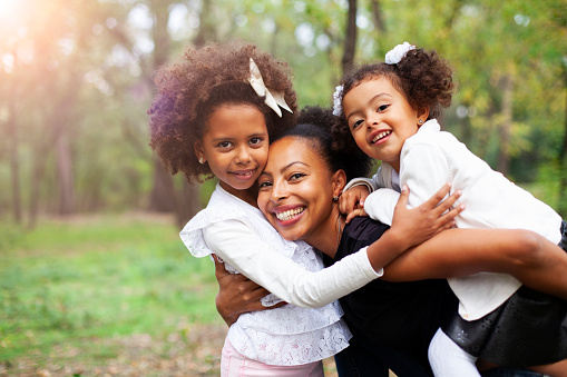 African-American mother and children hugging in the park