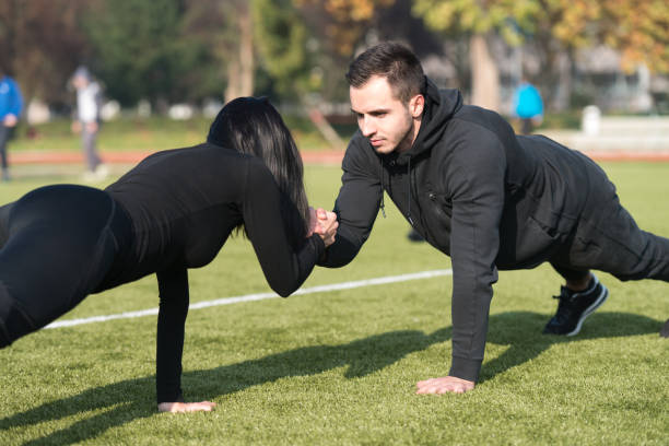 istock Sports Couple Doing Pushups in the Park 1255812088