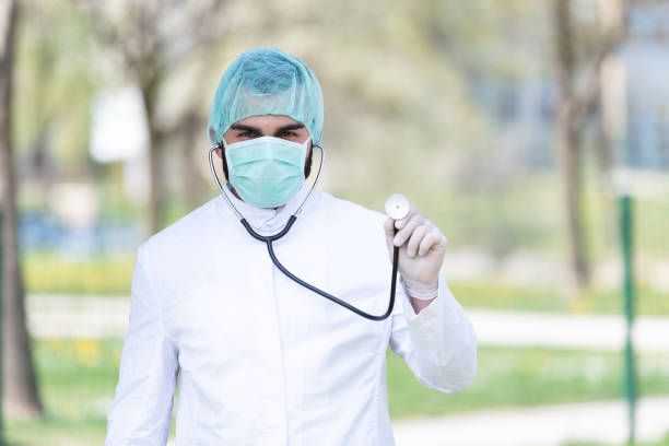 Portrait of a Tired Exhausted Male Caucasian Doctor in Front of a Park - Coronavirus Covid-19 Virus Disease - Global Pandemic Outbreak