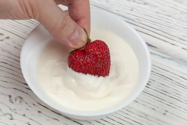 Photo of Men's hand dips strawberries into sour cream