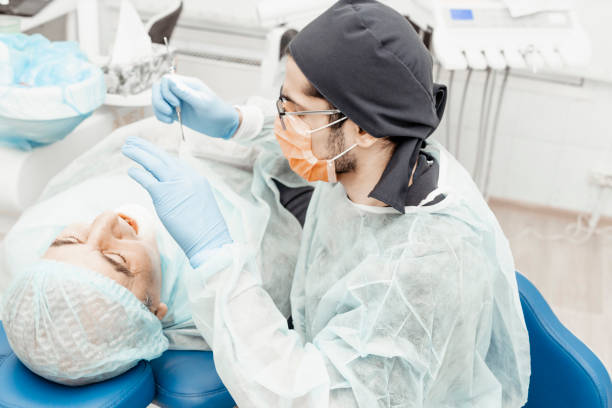 istock Patient and dentist during implant placement operation. Real operation. Tooth extraction, implants. Professional uniform and equipment of a dentist. Healthcare Equipping a doctorâs workplace. Dentistry 1255813481