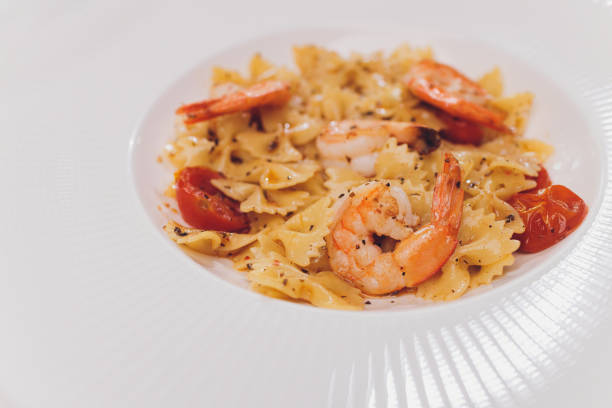 istock Pasta bavette with fried shrimps, bechamel sauce, mint leaf, garlic, tomatoes, chili on white plate, top view, italian cuisine. 1255814638